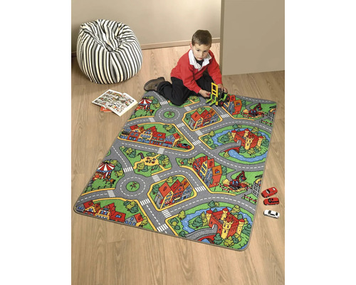 Koberec na hraní se vzorem silnice a dítě si hraje s autíčky a hračkou bagru