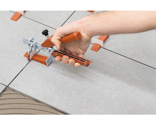 Ruka používá nivelační systém na dlaždice