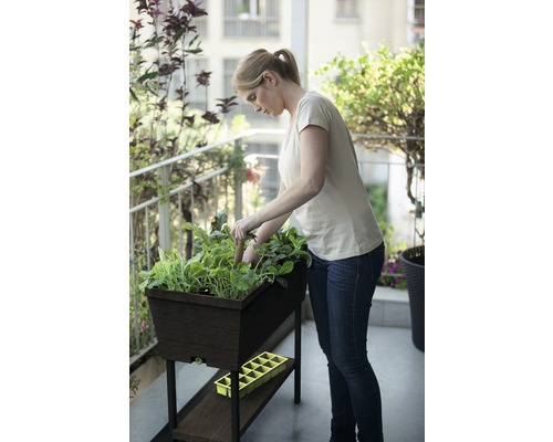 Žena zahradničí ve vyvýšeném záhonu na balkoně.