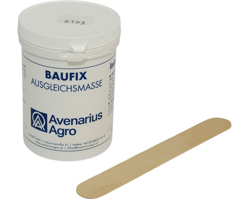 Vyrovnávací hmota pro instalaci keramických výrobků Laufen Vyrovnávací hmota Baufix v bílé nádobě s dřevěnou špachtlí.