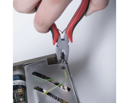 Kleště stříhají součástku z elektronického zařízení.
