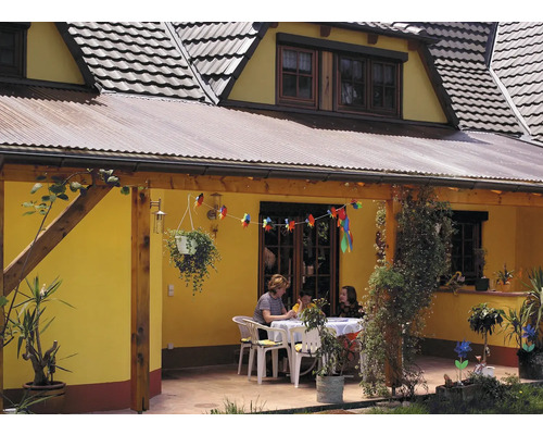 Dům s krytou terasou, stolem, židlemi a okrasnými rostlinami