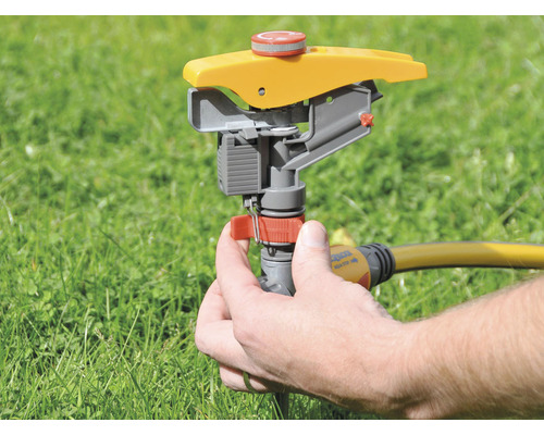 Zahradní postřikovač s rukou na trávníku