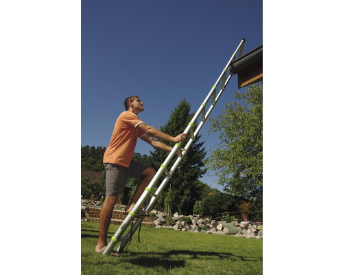 Muž leze po výsuvném žebříku na zahradě