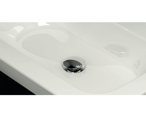 Detailní pohled na bílé umyvadlo s chromovanou výpustí