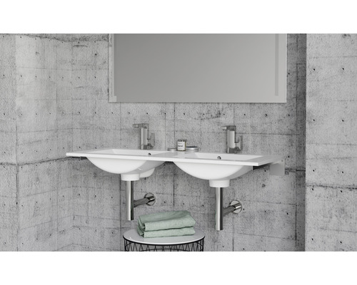 Koupelna s dvojitým umyvadlem, bateriemi a zrcadlem před betonovou stěnou