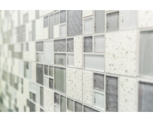 Detailní záběr stěny s mozaikovými obklady v různých odstínech šedé a texturách.