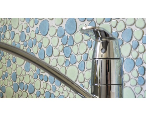 Detail vodovodní baterie před stěnou s mozaikovými dlaždicemi s oblázkovým vzorem