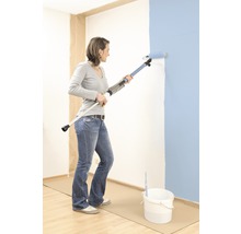 Žena maluje stěnu válečkem s teleskopickou tyčí