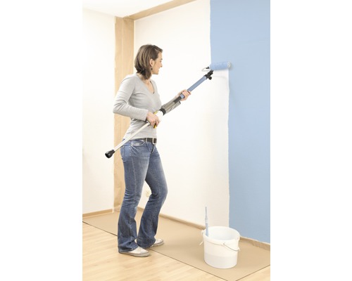 Žena maluje stěnu válečkem s teleskopickou tyčí