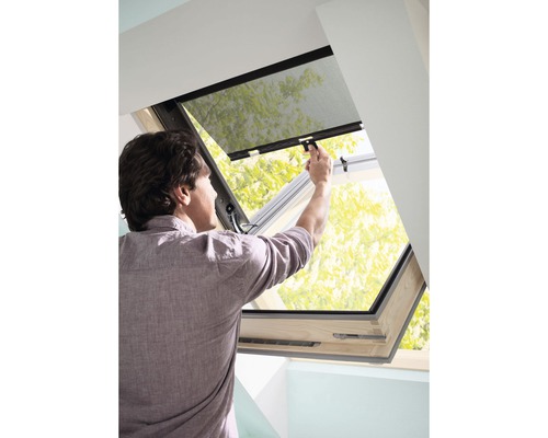 Muž ovládá střešní okno s ochranou proti hmyzu