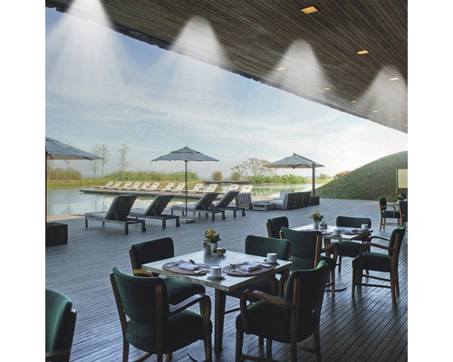 Venkovní prostor se stoly, židlemi, slunečníky a lehátky u jezera