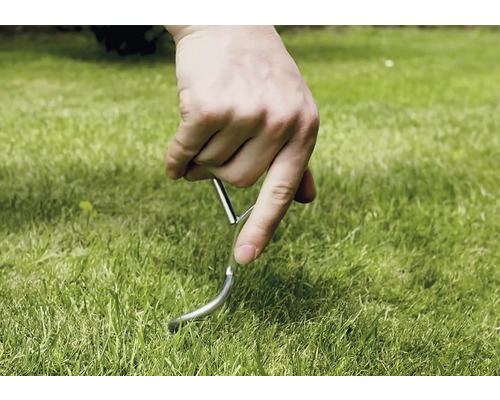 Ruka zapichuje kolík do trávníku