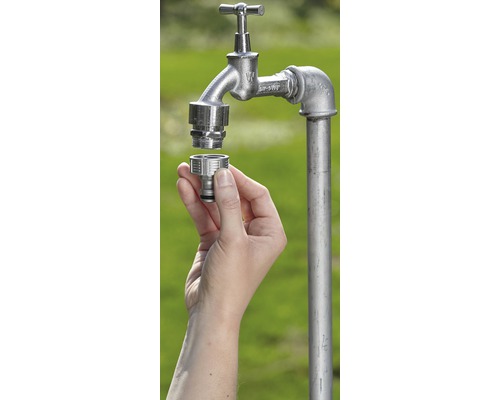 Ruka montuje hadicovou spojku na zahradní vodovodní kohoutek.