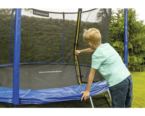 Chlapec u trampolíny se sítí na zahradě.