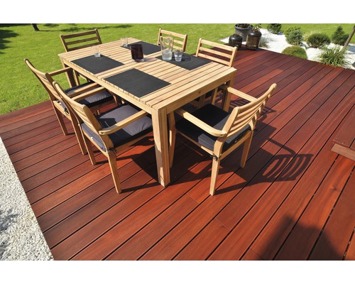 Zahradní scéna s dřevěnou terasou a jídelní soupravou se šesti židlemi.