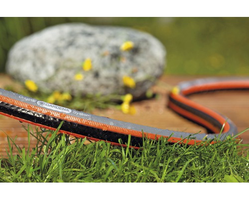 Zahradní hadice Gardena na trávníku s kamenem v pozadí