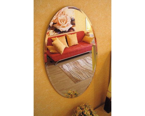 Oválné zrcadlo na zdi odrážející pokoj s pohovkou a kobercem