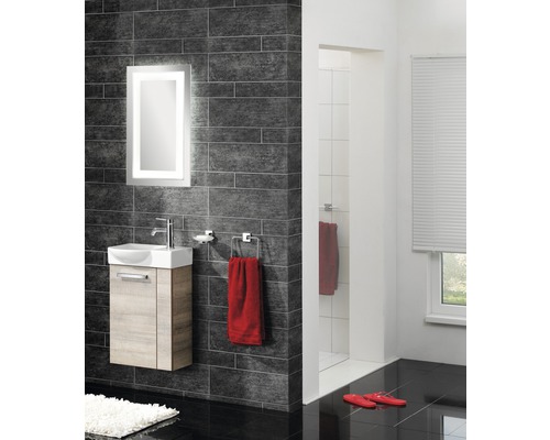 Moderní koupelna s umyvadlem, osvětleným zrcadlem a tmavými obklady