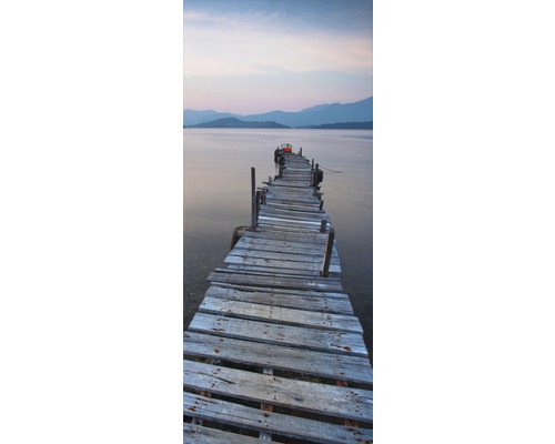 Dřevěná lávka vedoucí do vody s horskou kulisou v pozadí