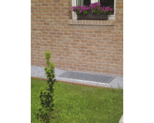 Venkovní fotografie okna sklepa s mřížkou a cihlovou zdí