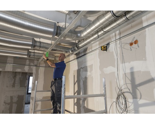 Instalatér montuje ventilační potrubí a spodní konstrukci ke stropu.