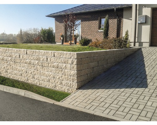 Betonový plot Duo Stone DS 400 okrová Dům s opěrnou zdí z kamenných bloků a dlážděnou příjezdovou cestou