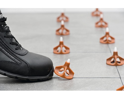 Systém vyrovnávání dlaždic s klipy pod pracovní obuví na dlaždicích