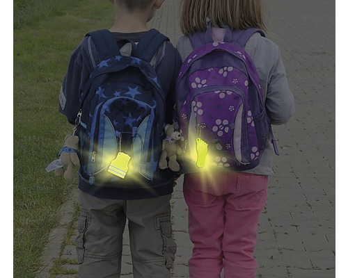 Děti se školními batohy a reflexními přívěsky pro zvýšení bezpečnosti