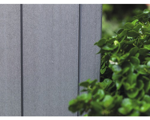 Detail plastového obkladu fasády vedle zelené rostliny