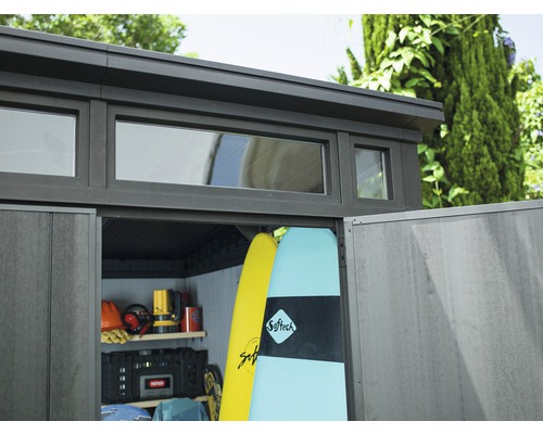 Zahradní kůlna s okny a otevřenými dveřmi, plná surfů a zahradního nářadí