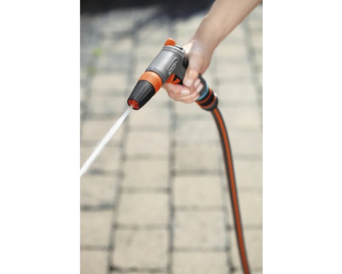 Ruka drží zahradní stříkací pistoli s proudem vody.