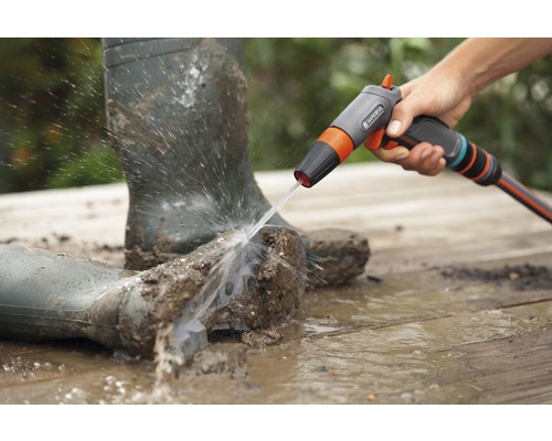 Špinavé gumové holínky jsou čištěny čisticím postřikovačem Gardena