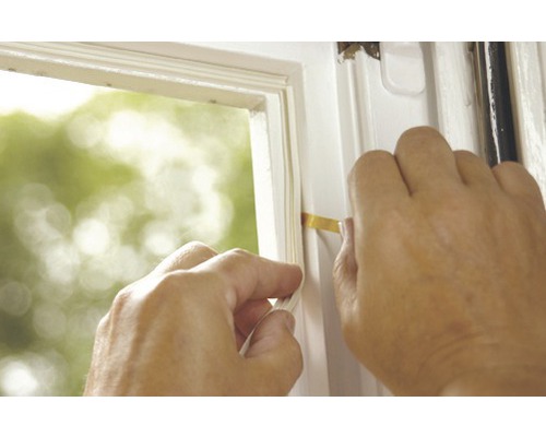 Osoba utěsňuje okno těsnicí páskou.