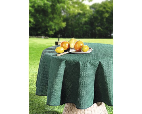 Kulatý zahradní stůl se zeleným ubrusem a ovocem