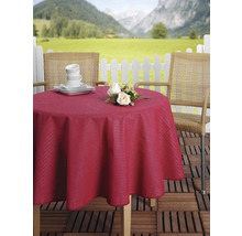 Prostřený zahradní stůl s červeným ubrusem, nádobím, květinami a dvěma židlemi venku s horami v pozadí.