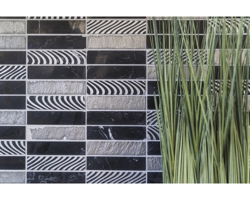 Dekorativní mozaikové dlaždice v černé, bílé a šedé barvě vedle okrasné trávy