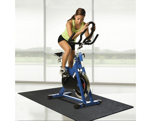 Žena cvičí na modrém spinningovém kole na černé podložce