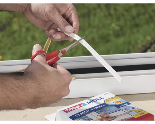 Osoba stříhá nůžkami těsnicí pásku Tesa Moll Classic P-Profile.