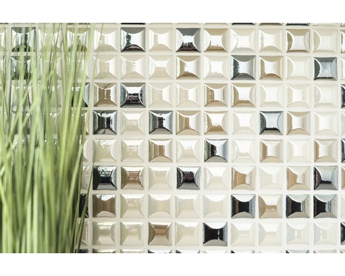 Detailní záběr stěny s mozaikovými dlaždicemi a okrasnou trávou