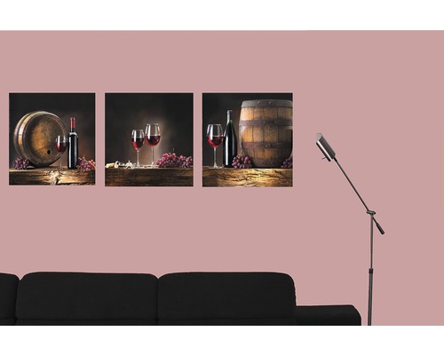 Dekorativní trojdílné nástěnné malby s motivy vína nad černou pohovkou.