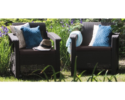 Dvě černá ratanová křesla s polštáři a doplňky na zahradě