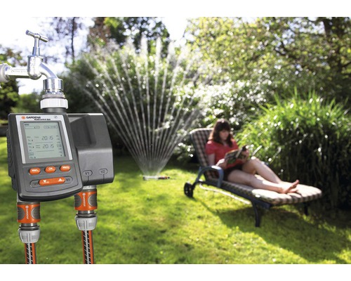 Řídicí jednotka zavlažování Gardena s připojením na vodovodní kohoutek na zahradě se zavlažovačem trávníku a relaxující ženou