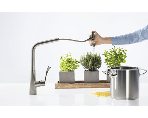 Kuchyňská scéna s výsuvnou kuchyňskou baterií, bylinkami a hrncem.