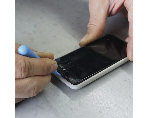 Řemeslník opravuje smartphone nástrojem, poškozený displej