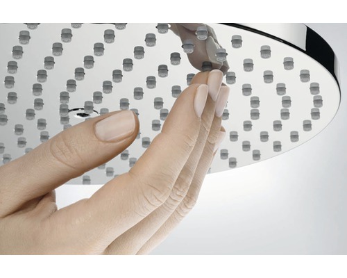 Ruka se dotýká sprchové hlavice s funkcí proti usazování vodního kamene