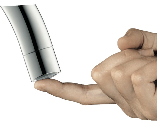 Detail konce vodovodní baterie, kterého se dotýká prst