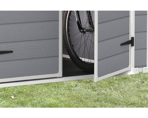 Detailní pohled na otevřený úložný prostor na zahradní nářadí s kolem uvnitř.