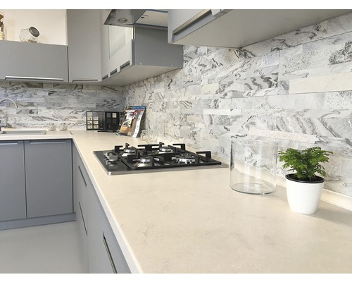 Moderní kuchyně se šedými skříňkami, pracovní deskou a obkladem v mramorovém vzhledu a plynovým sporákem.