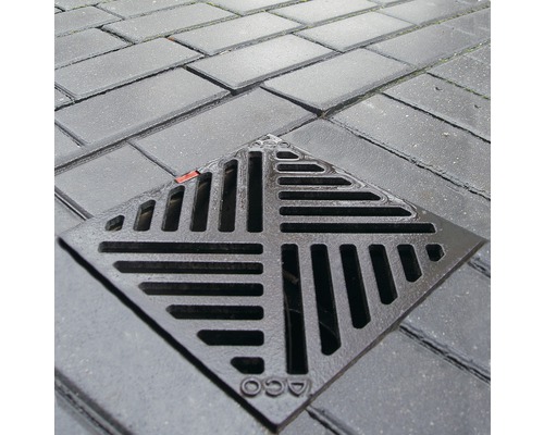 Logo Aco na litinové mřížce dvorní vpusti v dlažbě